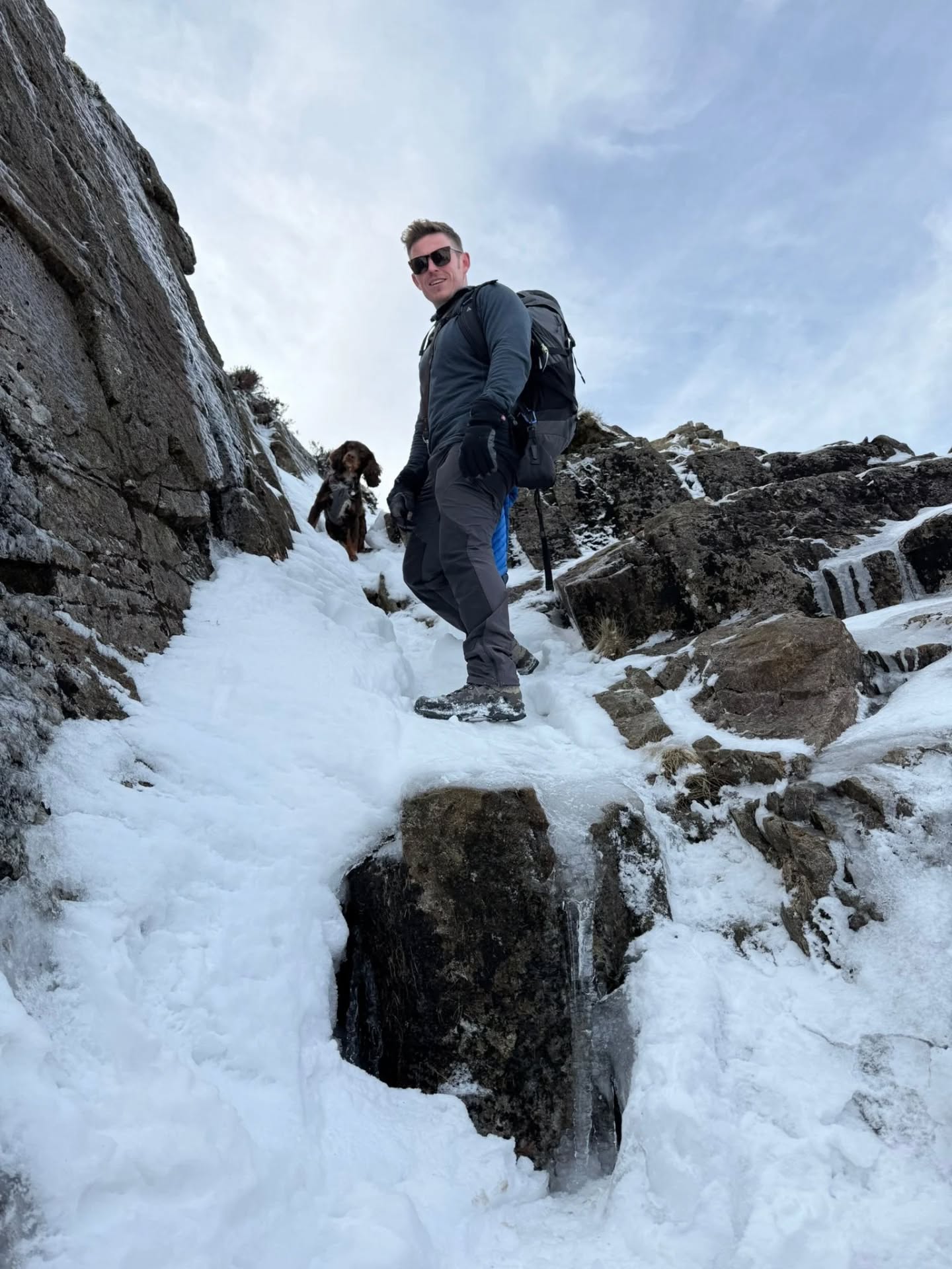 Stuart Lye scrambling up a snowy mountain route with his dog Reggie