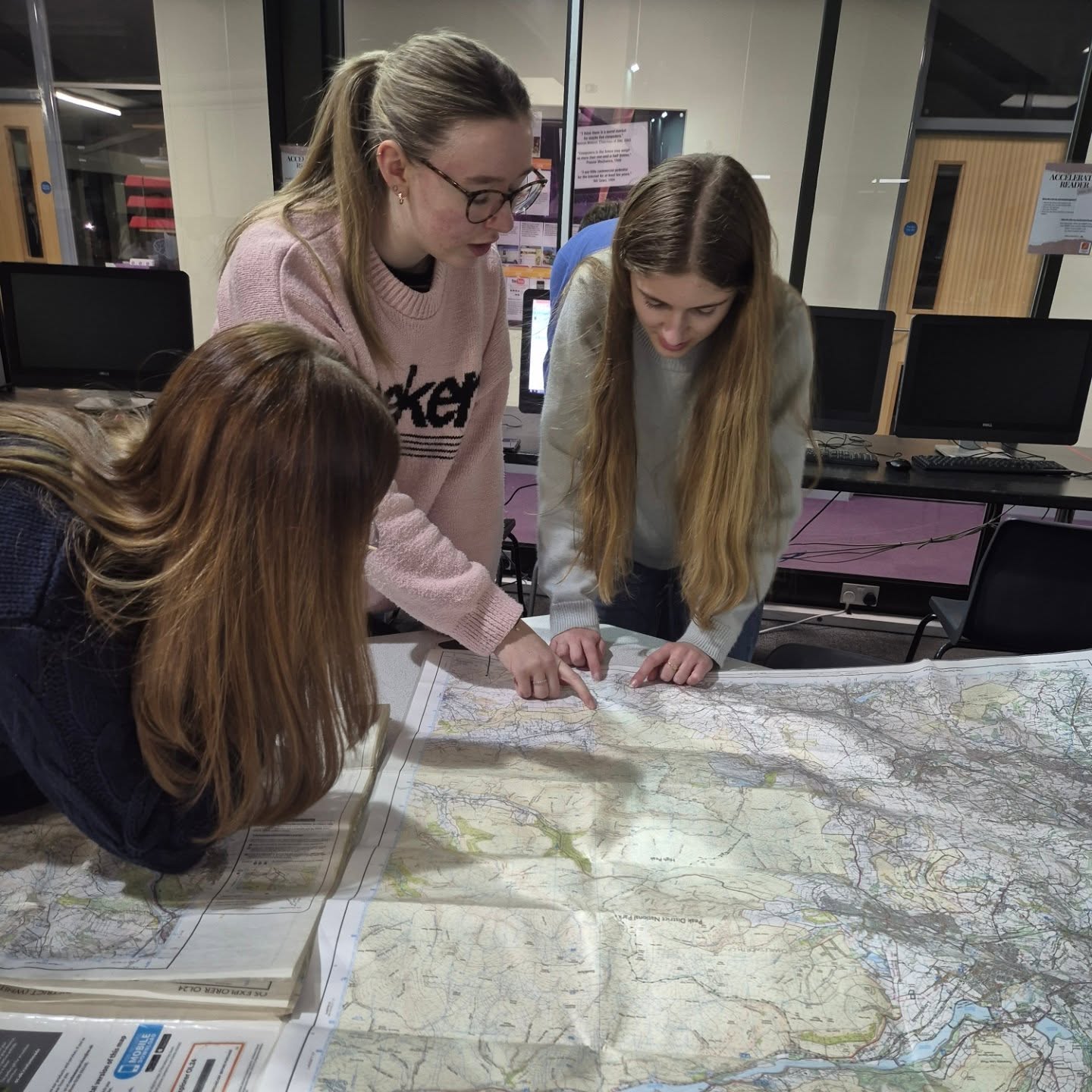 Dark Peak Expeditions students studying an Ordnance Survey map together during a route-planning session